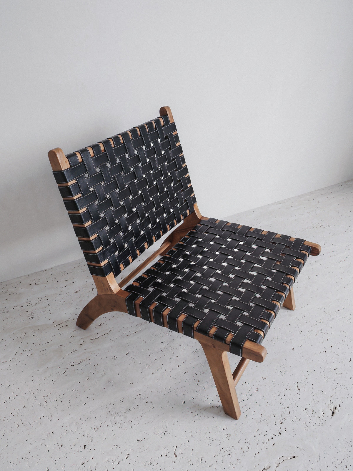 Low lounge chair in walnut and woven leather, side view of the reclined profile