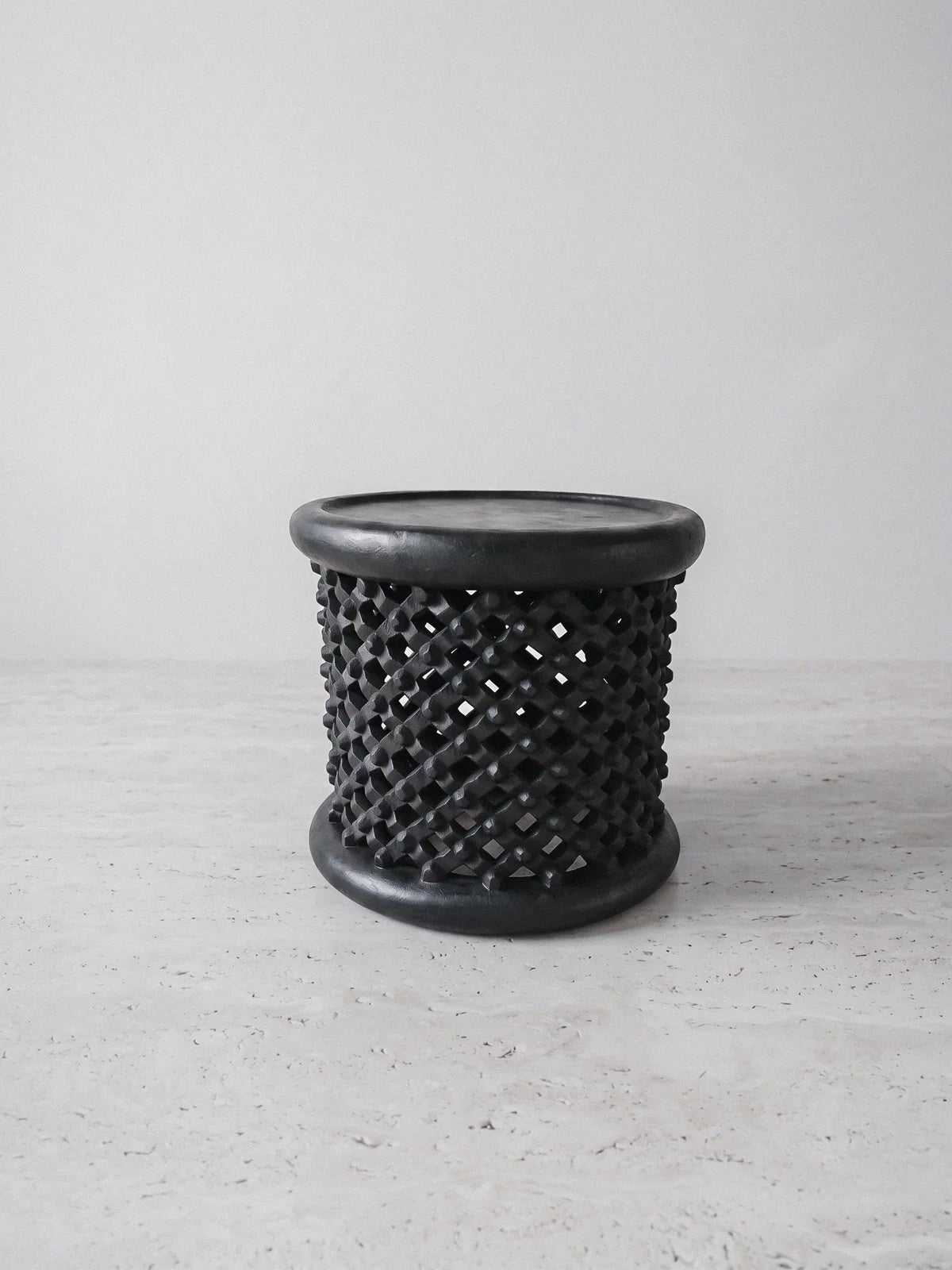 Sculptural monolithic stool by Casarin, ebonized hand-carved timber with openwork lattice body